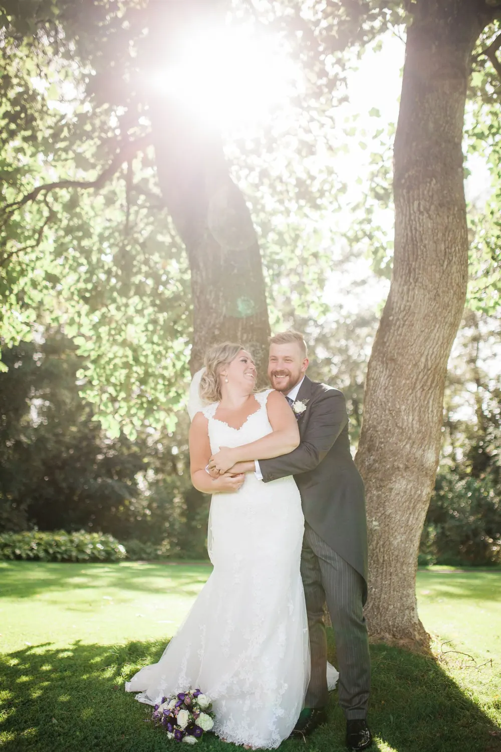 Bride and groom under a tree against the light